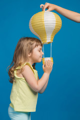 little girl touches a yellow balloon, looks inside the basket with interest, concept of adventure and fantasy
