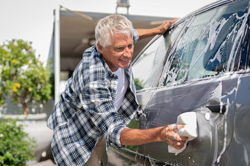 Smiling man washing his car