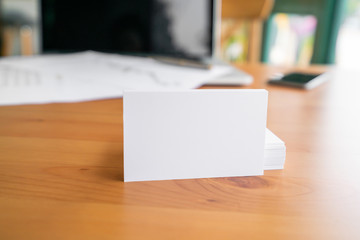 Blank business cards and laptop on wooden surface