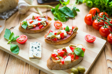 Fototapeta na wymiar Toasted ciabatta, a cheese sandwich with mold, tomatoes, basil on a wooden background.