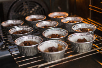 Raw muffins in the forms in the oven. Cooking chocolate muffins.