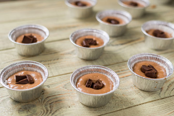 Raw dough for cooking in baking dish on wooden background. Cooking chocolate muffins.