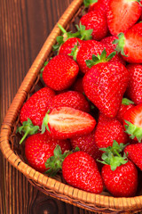 Juicy washed strawberries in wooden bowl on kitchen table.