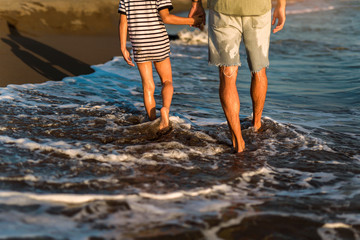 Fototapeta premium Father and son, man & boy child, running and having fun in the sand and waves of a sunny beach