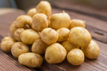 Closeup of a pile of new potatoes on a rustic wooden board.