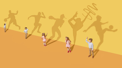 Childhood and dream concept. Conceptual image with children and shadow on the yellow studio wall. Little girl and boy want to become gymnast, dancer, artist, boxer, runner or football player.
