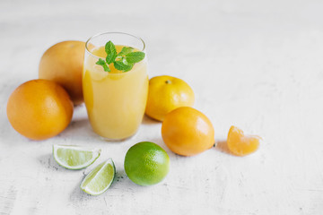 Orange juice and citrus fruits grapefruit, tangerine, lemon and lime on a white bright background