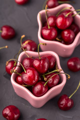 ripe and juicy cherries in a pink plate and scattering, the shape of star. Gray, cement table, postcard