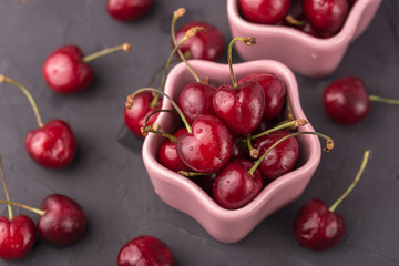 ripe and juicy cherries in a pink plate and scattering, the shape of star. Gray, cement table, postcard