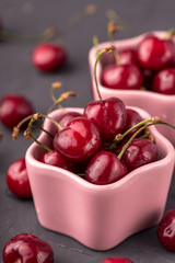 ripe and juicy cherries in a pink plate and scattering, the shape of star. Gray, cement table, postcard
