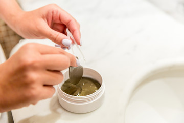 girl pulls out eye patches from the box in bathroom. Morning spa concept