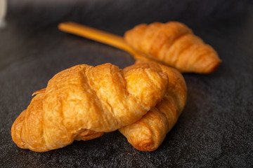 Croissants with white coffee cups with flour and eggs on a black background, breakfast, brown bread, morning drinks Concept: Delicious food for health, pastry, bakery, restaurant, lifestyle area