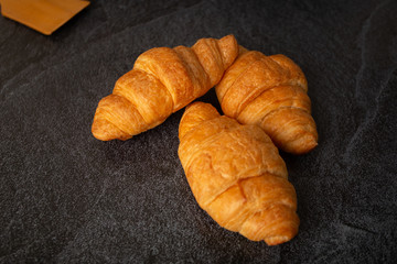 Croissants with white coffee cups with flour and eggs on a black background, breakfast, brown bread, morning drinks Concept: Delicious food for health, pastry, bakery, restaurant, lifestyle area