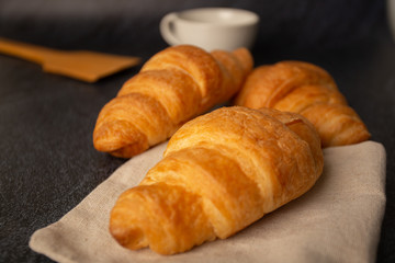 freshly baked croissants on a black background with a white coffee cup,breakfast bread brown beverage morning,Concept: meal delicious for healthy,Dessert bakery restaurant  lifestyle of the copy area