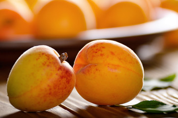 Clay dish full of ripe apricots on wooden table