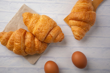 Croissants with coffee cups with flour and eggs on a white background, breakfast, brown bread, morning drinks, fantasy world: delicious food for health, pastries, bakery, restaurants, lifestyle areas