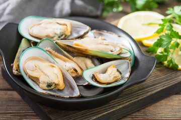 Raw kiwi mussels on a wooden Board on a wooden table. Rustic style