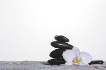 Orchid and stones on grey towel