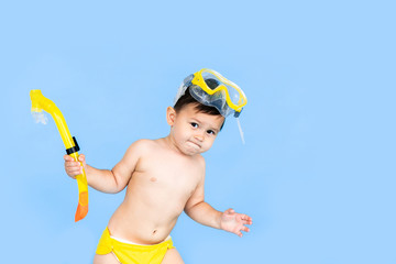 Beach vacation funny baby boy with mask tube for swimming in sea water. Portrait of a child on blue background