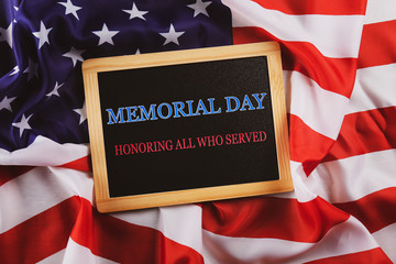 Memorial day weekend text written on wooden black chalkboard with USA flag. United States of America stars & stripes patriot veteran remembrance symbol. Background, close up, copy space, top view.