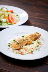 chicken kebab with rice and vegetables on the wooden background