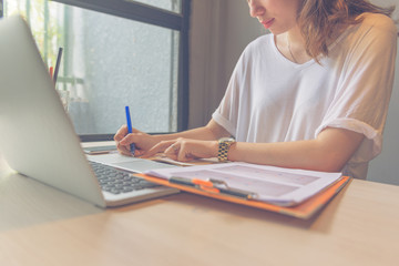 Woman handwriting into the financial report document