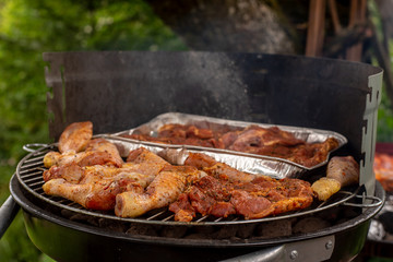 a small grill full of roasted meat on the background of nature, in the summer, warm evening