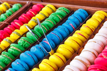 Colorful macaroons. Traditional sweets with silver tongs
