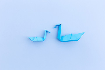 Fototapeta premium A swan with child of paper on a blue background, origami