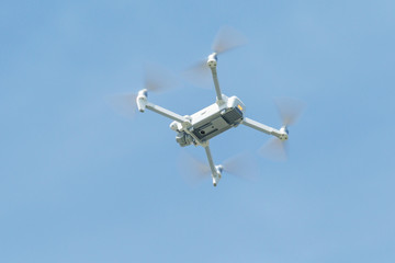 Professional filming drone flies in the air at a low altitude against a blue sky. Drone makes photos. Modern new technology. Ready background with place for your text