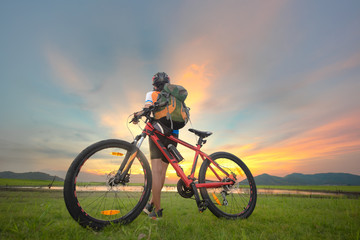Woman cyclist bicycle paused riding on the meadow field, looking for forward ahead possibility cross the lake,  adventure woman riding mountain bike alone in meadow at countryside