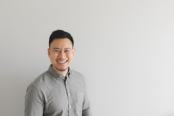 Happy and laughing face of ordinary man in grey shirt. Concept of charming laugh.