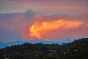 Colourful sunset over trees, houses and mountains in a summer time on a tropical island	