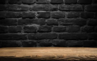 Obraz premium Old wood table with blurred concrete block wall in dark room background.
