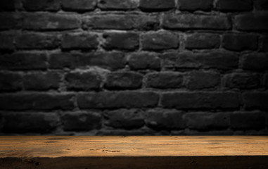 Old wood table with blurred concrete block wall in dark room background.