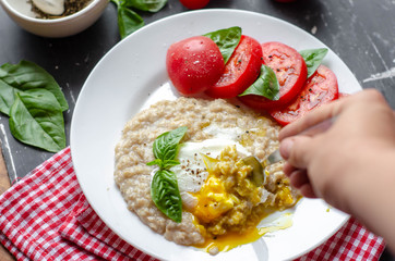 oatmeal with poached egg, tomatoes and basil. fresh tasty proper nutrition meal. healthy food for breakfast