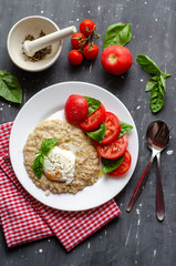 oatmeal with poached egg, tomatoes and basil. fresh tasty proper nutrition meal. healthy food for breakfast