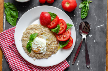 oatmeal with poached egg, tomatoes and basil. fresh tasty proper nutrition meal. healthy food for breakfast