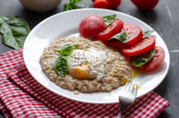 oatmeal with poached egg, tomatoes and basil. fresh tasty proper nutrition meal. healthy food for breakfast