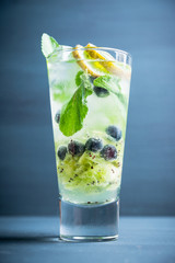 Fresh summer cocktail with blueberry and kiwi on the wooden background. Selective focus. Shallow depth of field. 