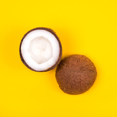 Top view of halved ripe coconut on bright yellow background. Copy space.