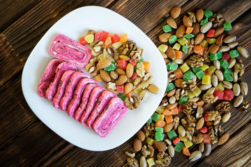 Arabian oriental sweets: extraordinary pink halvah in a white plate next to pistachios, almonds, walnuts and candied fruits. National cuisine of the Middle East
