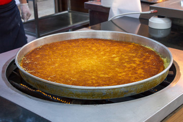 Traditional Turkish dessert kunefe in a large metal tray