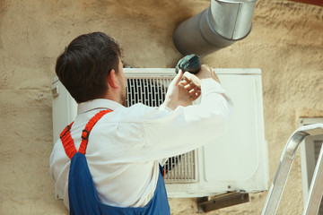 HVAC technician working on a capacitor part for condensing unit. Male worker or repairman in...