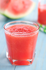 Refreshing watermelon juice on blue wood (Selective Focus, Focus on the front of the glass rim)