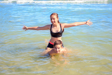 Young and happy teenagers boy and girl playing in the sea