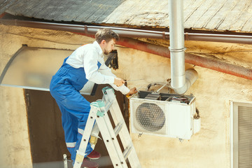 HVAC technician working on a capacitor part for condensing unit. Male worker or repairman in...
