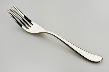 One dining fork resting on a gray surface