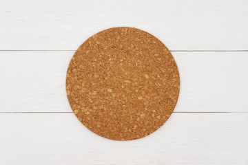 Empty round cork coaster on white wooden table. Top view image.