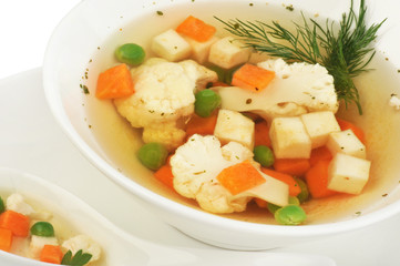 Vegetable soup with cauliflower, potatoes, peas, carrots and dill on a white isolated background